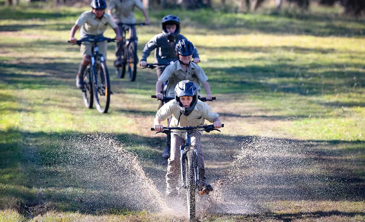 Tudor House student leading others on his bike riding through mud
