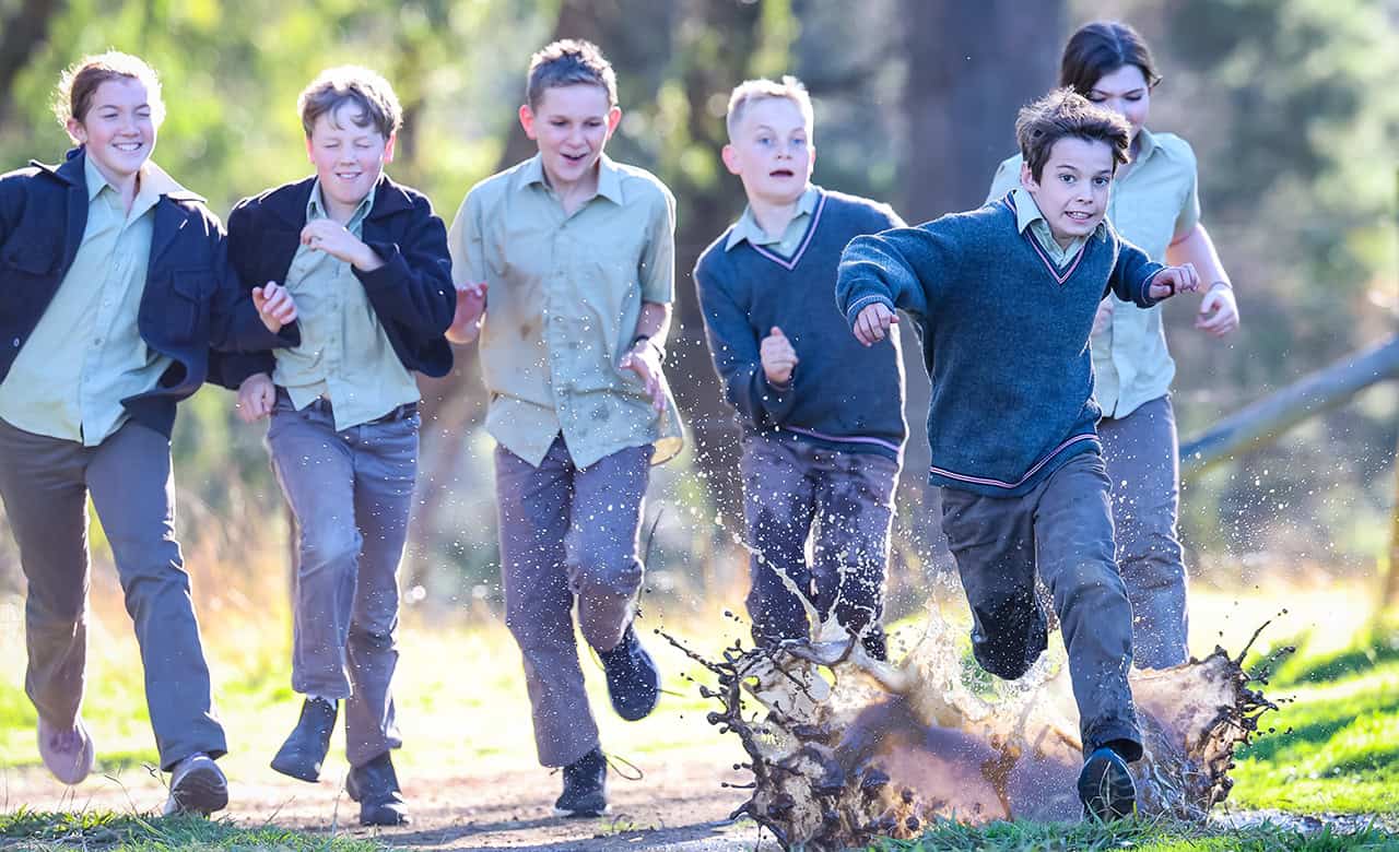 Tudor House students running towards the camera through mud