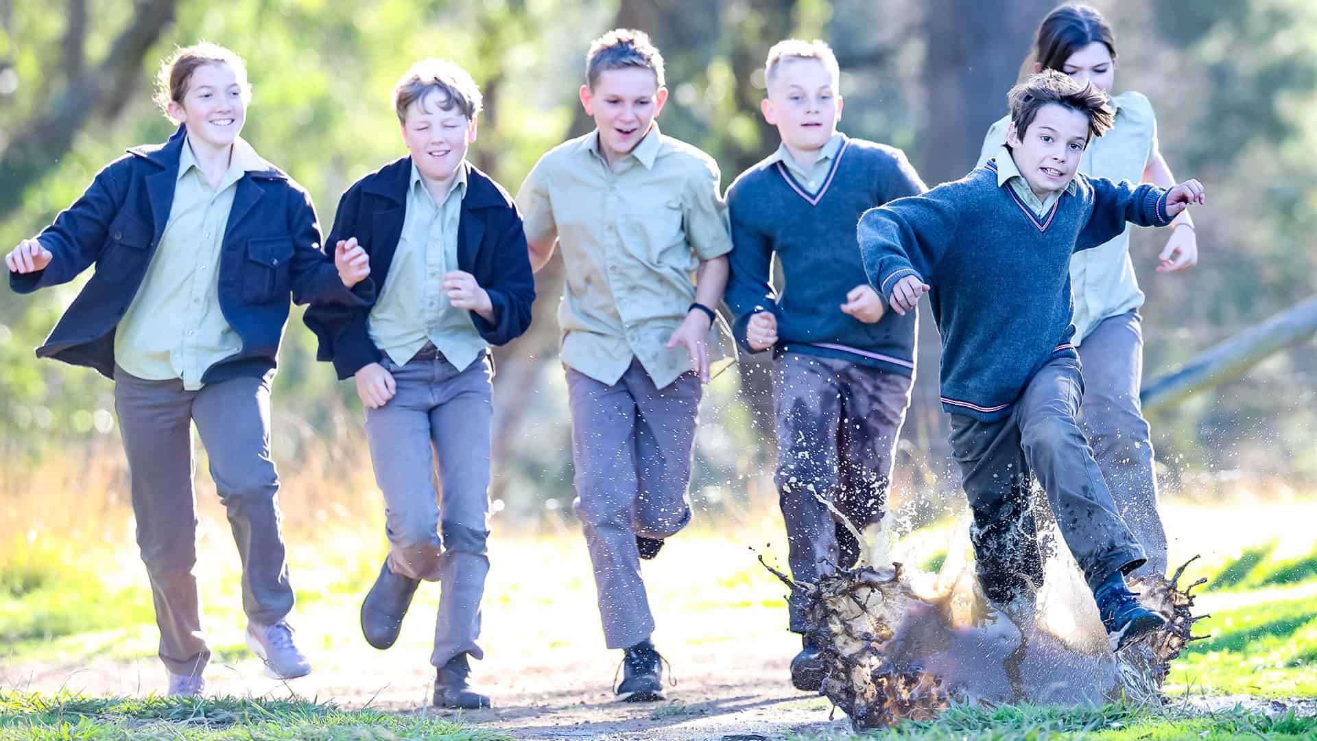 Tudor House Students in their uniforms running down a muddy path