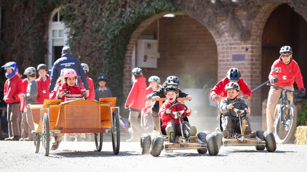Tudor House students sitting in go carts at Billy Cart Derby, smiling and ready to race